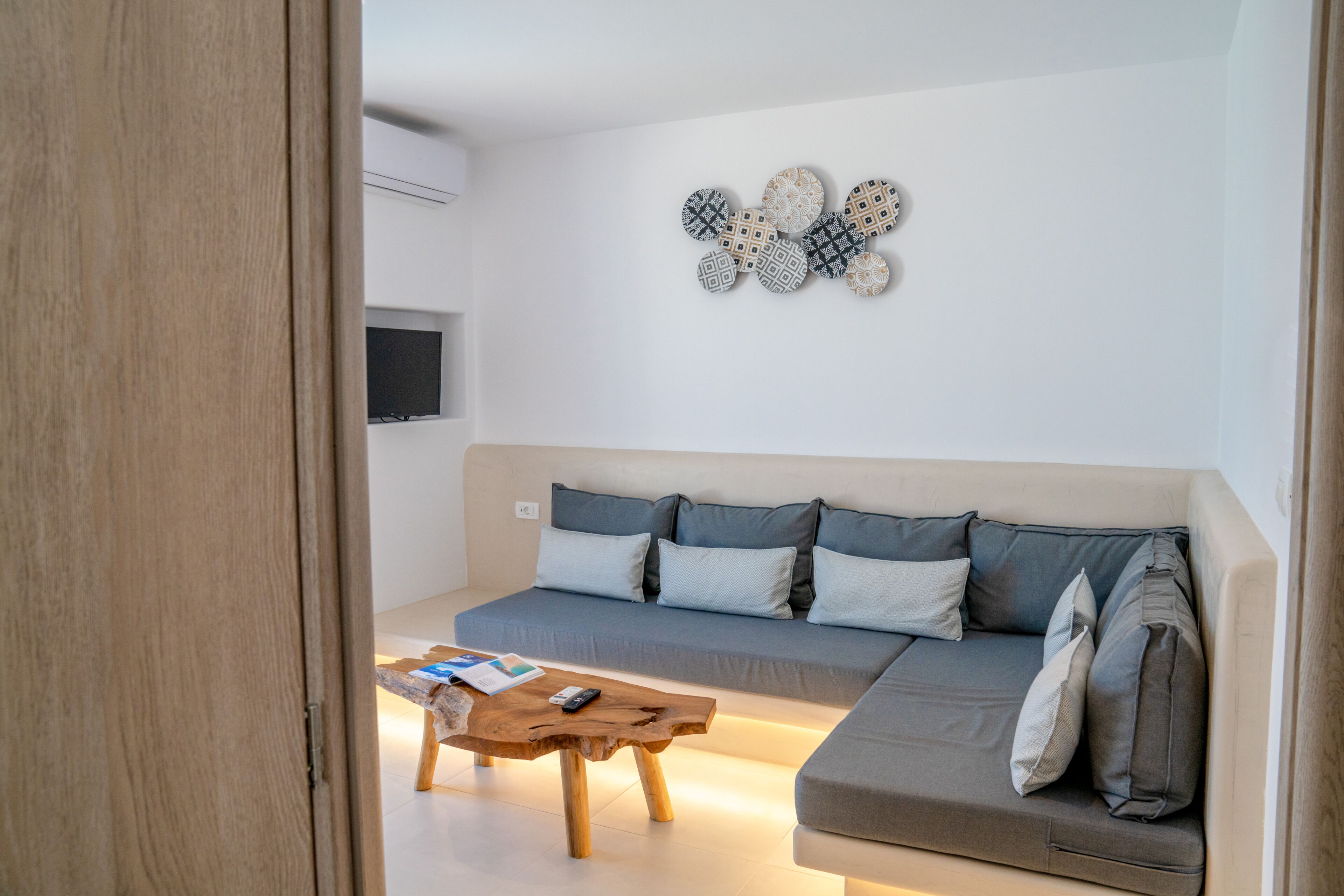 A modern living room with a grey sofa, a wooden coffee table, and a wall-mounted decorative piece.