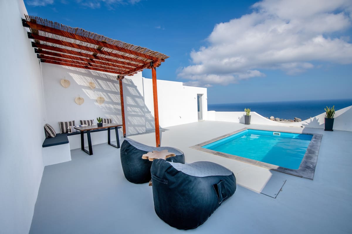 A rooftop pool area with a pergola, seating, and a view of the ocean.