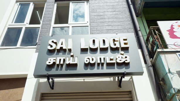 A sign for Sai Lodge with a modern design and a balcony. - Sai Lodge (Tiruchirappalli)