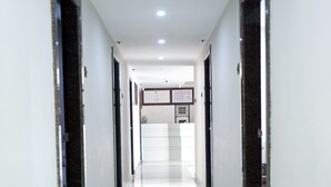 A long, narrow hallway with a shiny, reflective floor and doors on either side. - Sai Lodge (Tiruchirappalli)