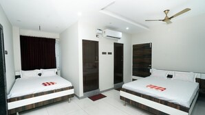 A hotel room with two beds, a ceiling fan, an air conditioning unit, and a red doormat. - Sai Lodge (Tiruchirappalli)