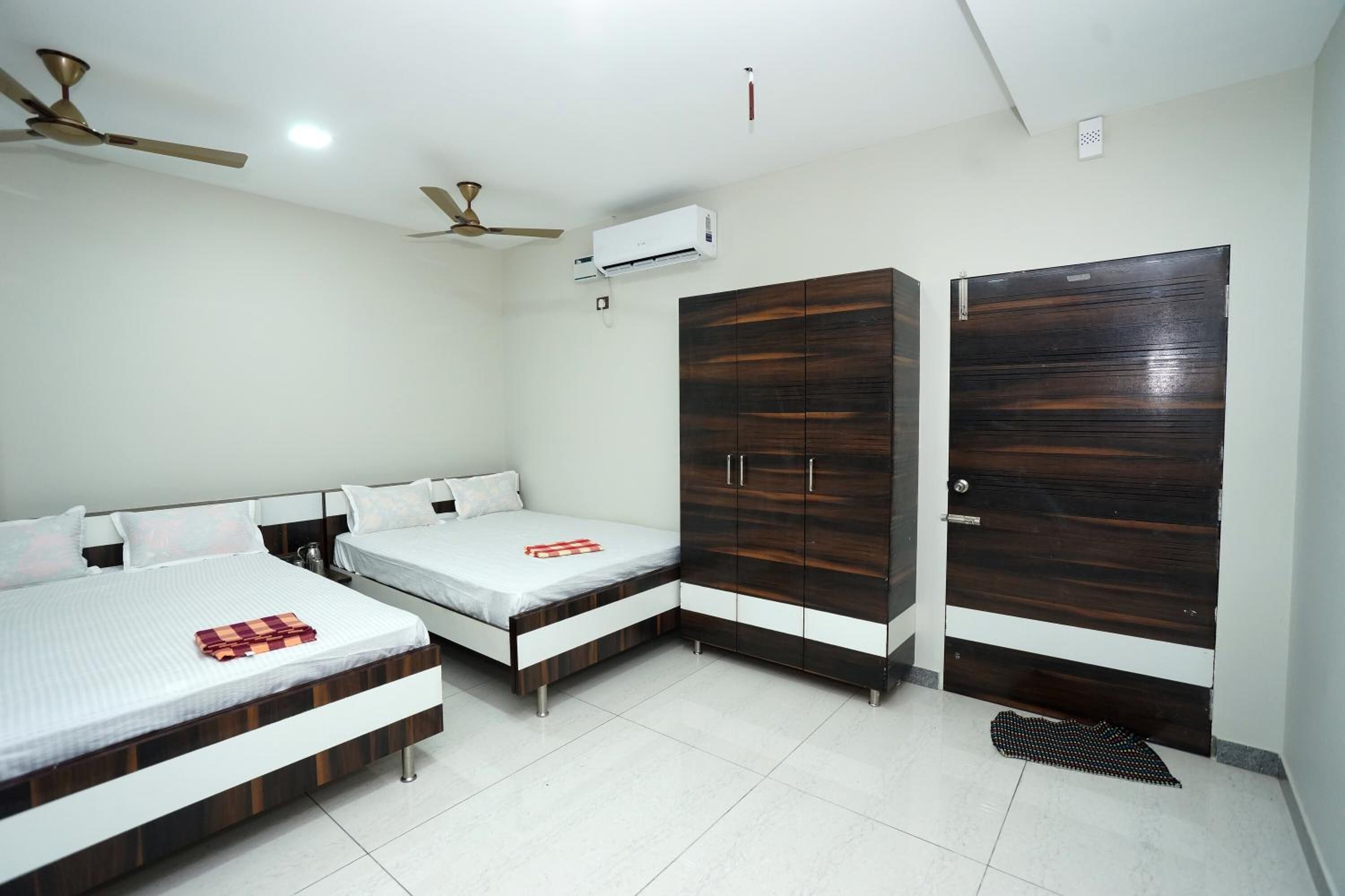 A bedroom with two beds, a wardrobe, and a ceiling fan.