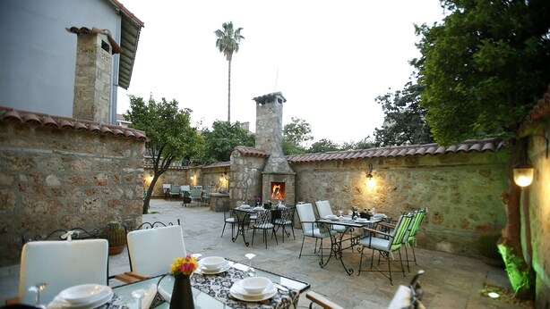 An outdoor patio with stone walls, a fireplace, and dining tables set for guests. - Castle Inn Boutique Hotel (Antalya)