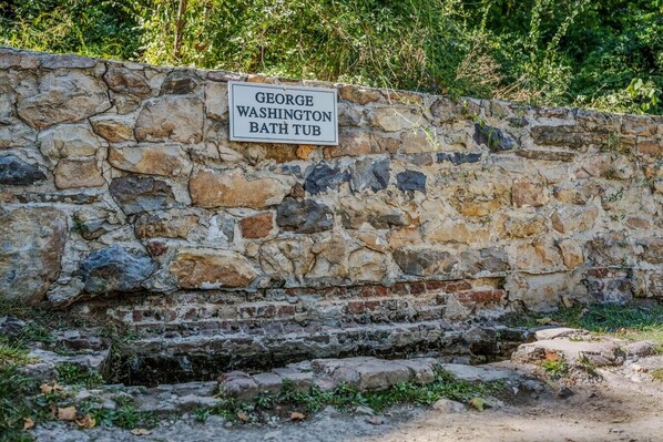 A stone wall with a sign reading 'GEORGE WASHINGTON BATH TUB.' - Namba Cabin - River Access | Pet Friendly | Grill | Wifi |Screen Porch (Great Cacapon)