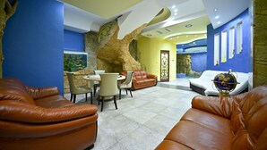 Un interior moderno con sofás de cuero, una pared de piedra y una zona de comedor.