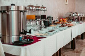 Een buffetopstelling met diverse drankdispensers en een scala aan gerechten op een lange tafel.