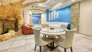 Un comedor con una mesa redonda, cuatro sillas y vistas a una pared azul con obras de arte.