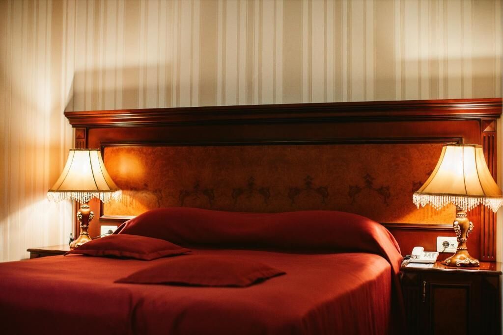 Une chambre d’hôtel avec un grand lit, deux lampes de chevet et une tête de lit en bois.