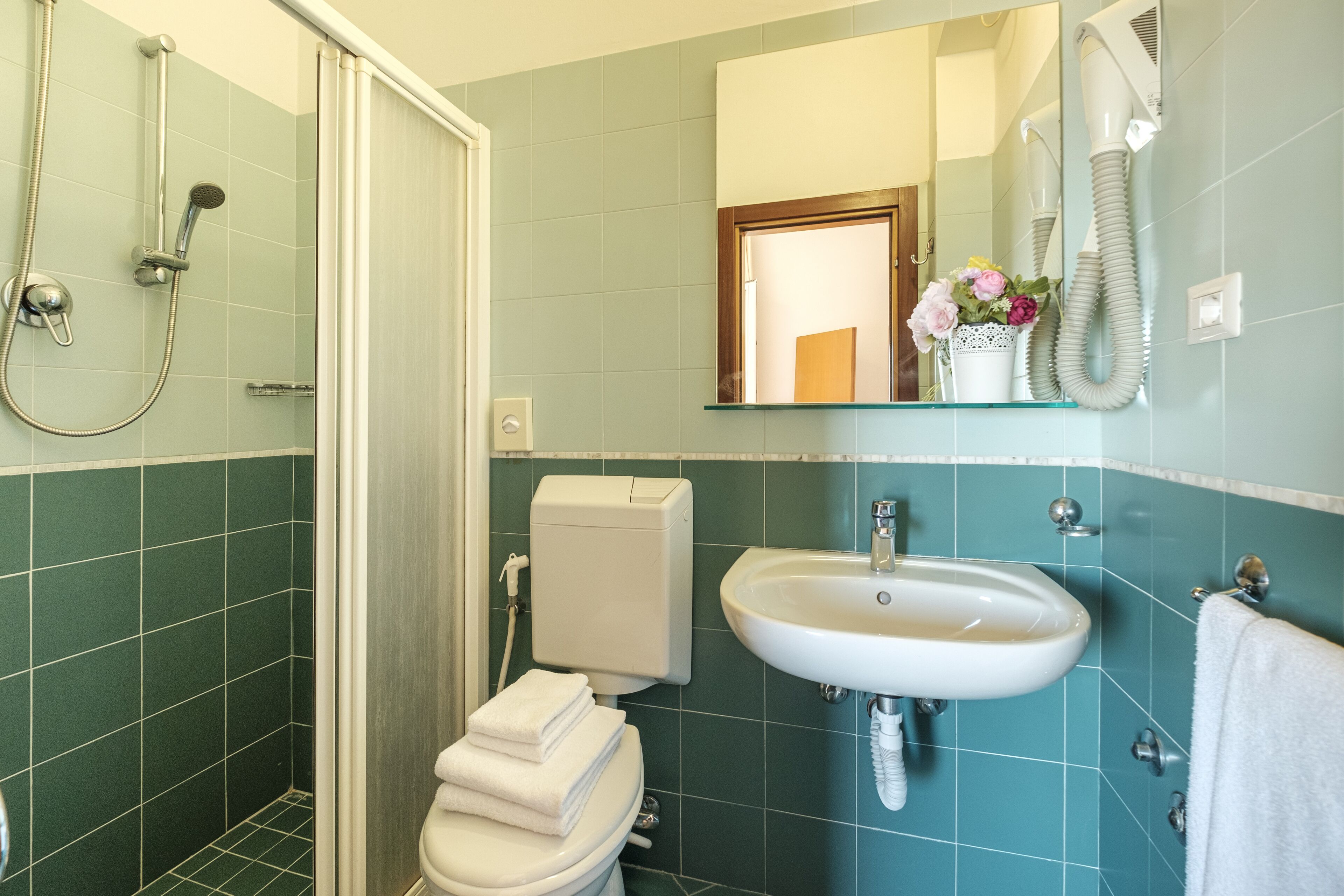 Un baño con ducha, inodoro, lavamanos y un espejo sobre el lavamanos.