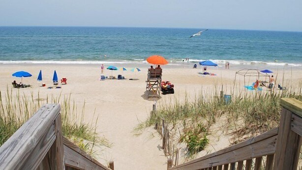 Une plage avec des parasols, des chaises longues et un poste de surveillance pour les sauveteurs.