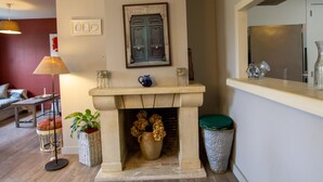 A living room with a fireplace, a sofa, a lamp, and a potted plant. - Renovated house with WiFi and terrace in Trélissac (Trélissac)