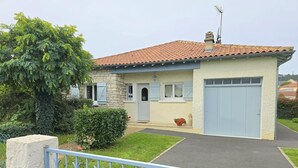 A two-story house with a red-tiled roof, a stone facade, and a light blue garage door. - Renovated house with WiFi and terrace in Trélissac (Trélissac)
