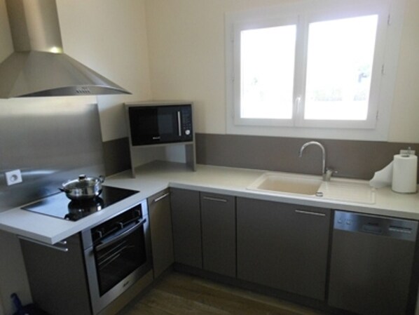 A compact kitchen with a stove, microwave, sink, and oven.