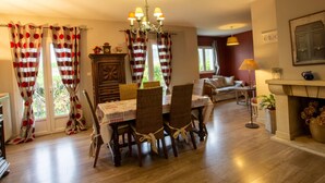 A dining area with a wooden table, chairs, and a chandelier. There is a sofa and a fireplace in the background. - Renovated house with WiFi and terrace in Trélissac (Trélissac)