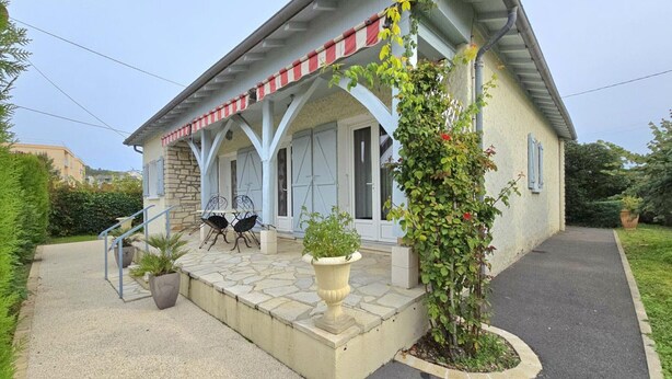 A two-story building with a stone facade, a covered porch with red and white striped awnings, and a small garden area with potted plants and a climbing vine. - Renovated house with WiFi and terrace in Trélissac (Trélissac)