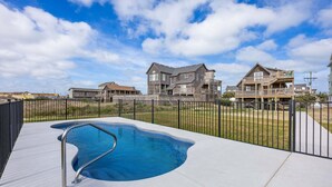 A swimming pool with a metal ladder, surrounded by a fence, with houses in the background. - 6129 Lady Jane * Semi-Oceanfront * Hot Tub (Nags Head)