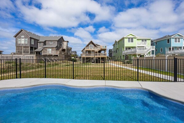 Zona residencial con piscina, casas con balcones y un patio cercado.