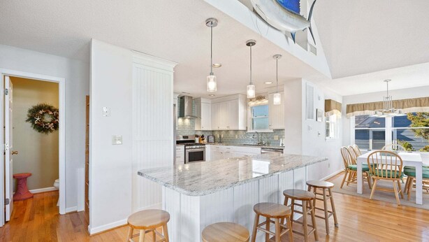 A spacious kitchen with a large island, wooden stools, and pendant lighting. - 6154 Little Sushi * 2 Min Walk to Beach (Nags Head)