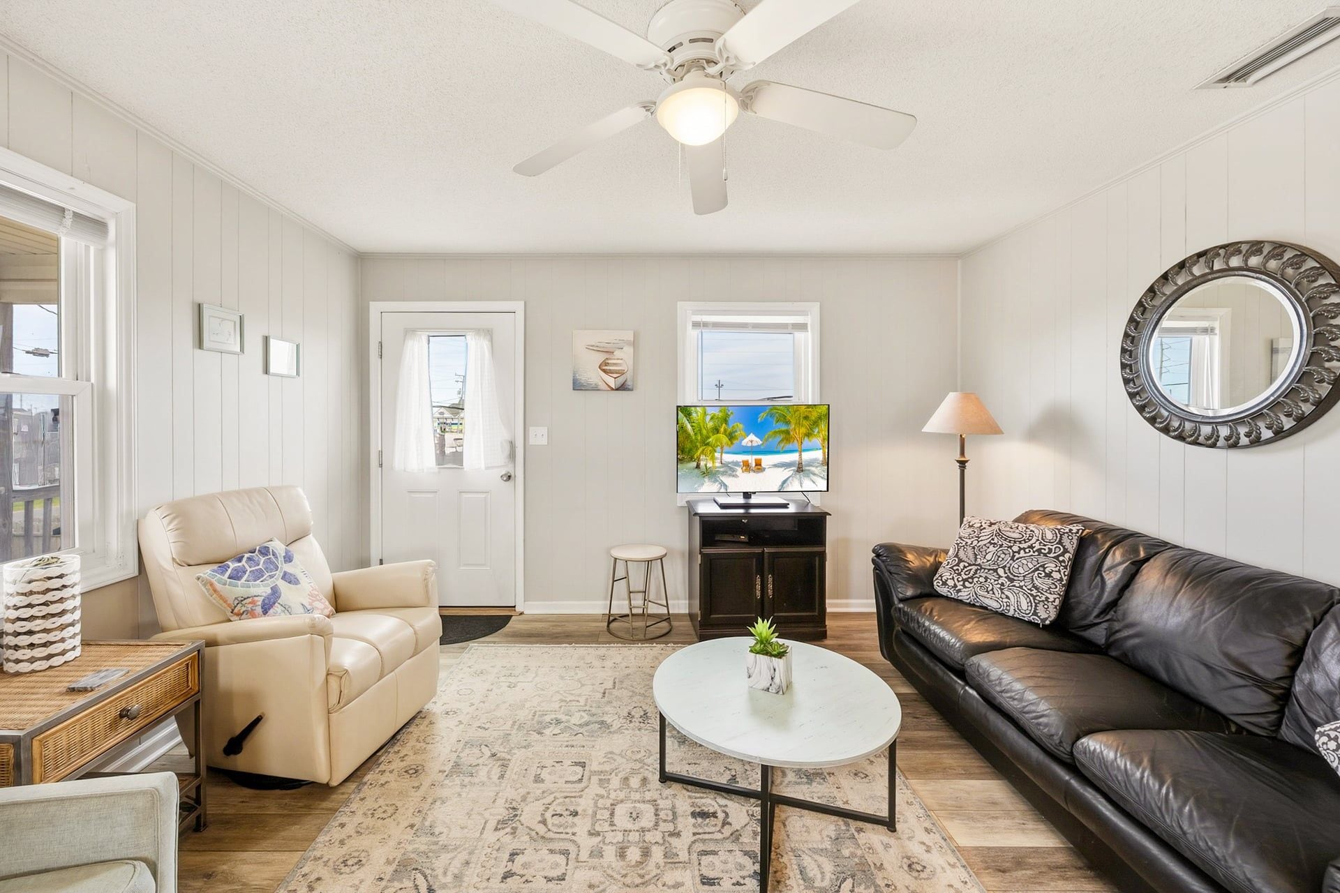 A living room with a ceiling fan, a television, a sofa, a coffee table, and a patterned rug.