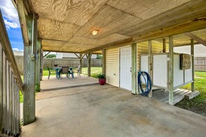 A covered patio area with a concrete floor, a table with chairs, and a potted plant. - High Five: Classic OBX Escape Near the Beach (Kill Devil Hills)