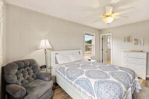 A bedroom with a bed, a chair, a dresser, a ceiling fan, and a window. - High Five: Classic OBX Escape Near the Beach (Kill Devil Hills)