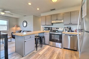 A modern kitchen with stainless steel appliances, a central island, and a dining area with a view.