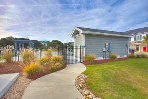 A residential building with a gated entrance, a small shed, and a well-maintained lawn.
