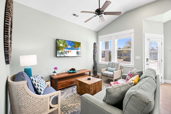 A living room with a sofa, coffee table, TV, and a ceiling fan.