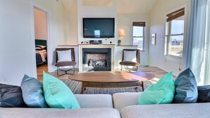 A living room with a fireplace, television, and two armchairs. - The Shake Shack: Dog-Friendly + 450ft to Beach (Kitty Hawk)