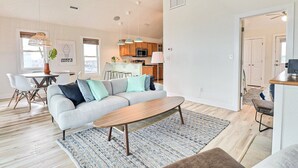 A modern living room with a sofa, coffee table, and dining area. - The Shake Shack: Dog-Friendly + 450ft to Beach (Kitty Hawk)