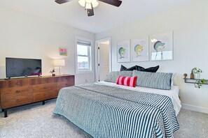 A bedroom with a bed, a dresser, a television, and artwork on the wall.