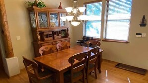 A dining area with a wooden table and chairs, a chandelier, and a cabinet with glass doors. - Great Cabin in Torreon Community of Show Low (Show Low)