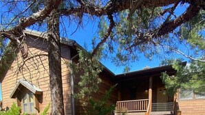 A cabin with a wooden exterior, a porch, and a stone pathway leading to the entrance. - Great Cabin in Torreon Community of Show Low (Show Low)