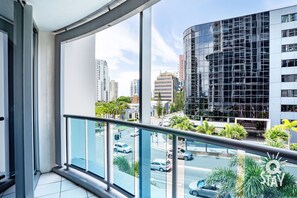 A balcony with a view of a cityscape, including modern buildings and a street with cars.