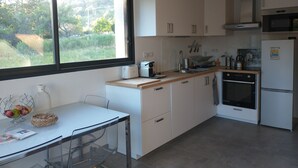 Eine moderne Küche mit weißen Schränken, einem Edelstahlbackofen, einer Mikrowelle und einem Fenster mit Blick auf Grünflächen.