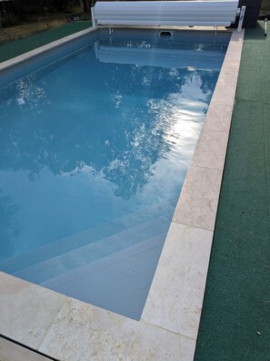 A swimming pool with a clear edge and a green artificial turf border.