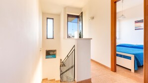 Un dormitorio con cama, ventana y una escalera que lleva a otra habitación.