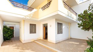 Una casa moderna de dos pisos con un patio empinado, un balcón y un pequeño jardín.