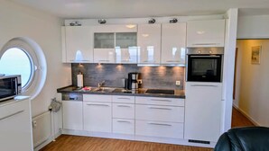 Una cocina compacta con gabinetes blancos, horno empotrado y ventana.
