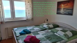 Un dormitorio con cama, ventana con cortinas, un cuadro y un radiador.