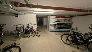 Ein Fahrradstellplatz mit mehreren Fahrrädern, einem Kajakständer und einem Betonboden.