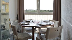 A dining area with a table set for four, a view of greenery outside, and a glass cabinet with decorative items.