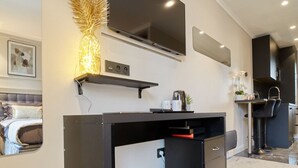 A modern kitchen with a flat-screen TV, a built-in oven, and a coffee machine.