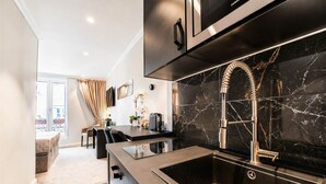 A modern kitchen with a black marble backsplash, stainless steel appliances, and a built-in sink. - Blackpearl-HyperKing Bed CenterSize-Parking Offered (Amiens)