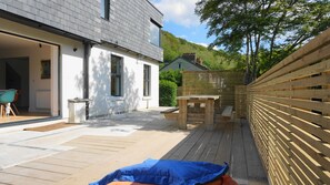 A modern house with a patio area, a wooden fence, and a view of a hill. - Echium Heights, 4 bed retreat, secluded with views (Ilfracombe)