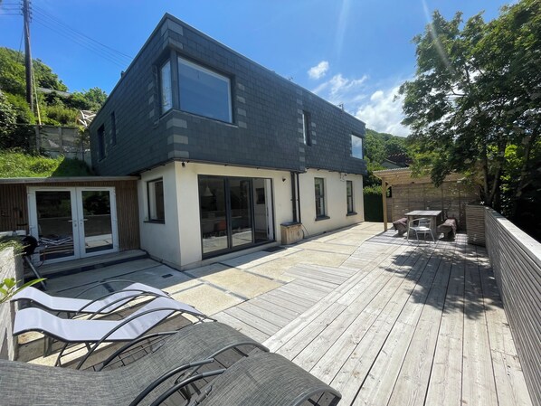 A modern house with a large deck, sliding glass doors, and a pergola. - Echium Heights, 4 bed retreat, secluded with views (Ilfracombe)