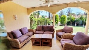 A room with a brown sofa set, a wooden coffee table, and wicker chairs.