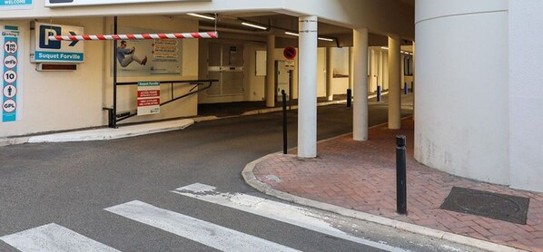 A parking entrance with a barrier gate, a sign for 'Suquet Forville', and a pedestrian crossing. - STUDIO MODERNE CENTRE CANNES A0B065 (Cannes)