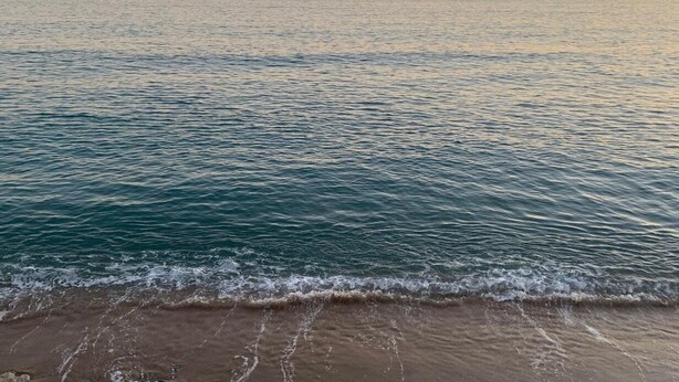 A beach with waves gently lapping onto the shore.