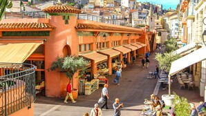 A bustling street with outdoor seating and market stalls.